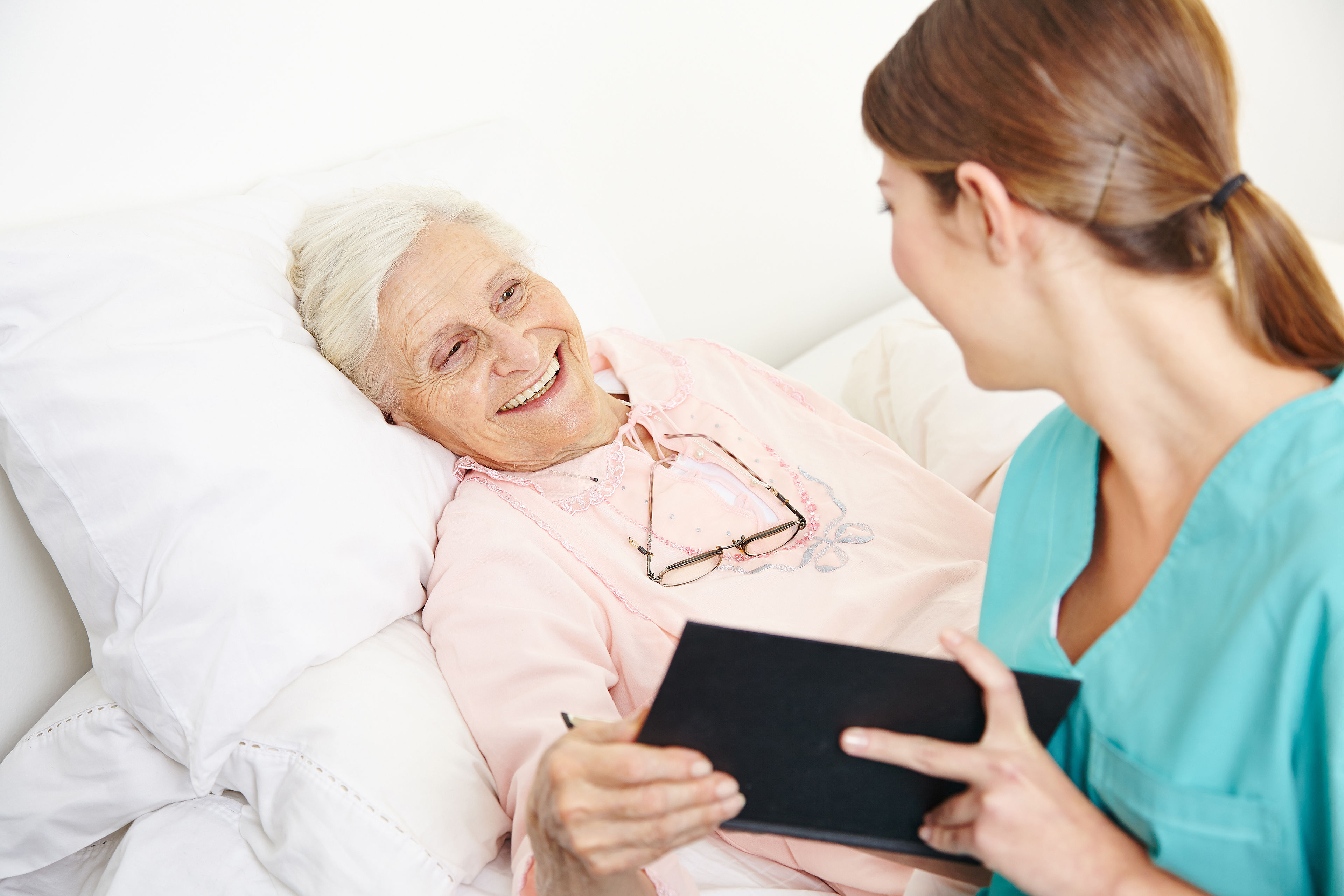 Krankenpflegerin liest Seniorin Buch vor